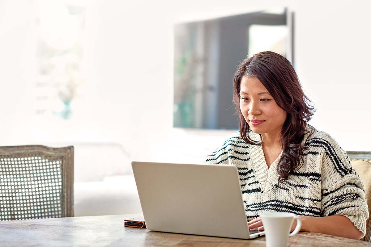 Woman sitting at dining room table on her computer