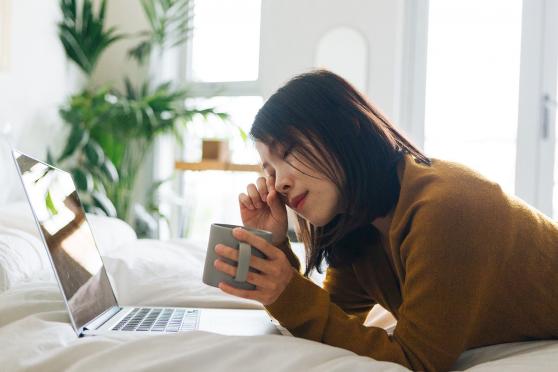 Sleepy woman with laptop rubbing eye