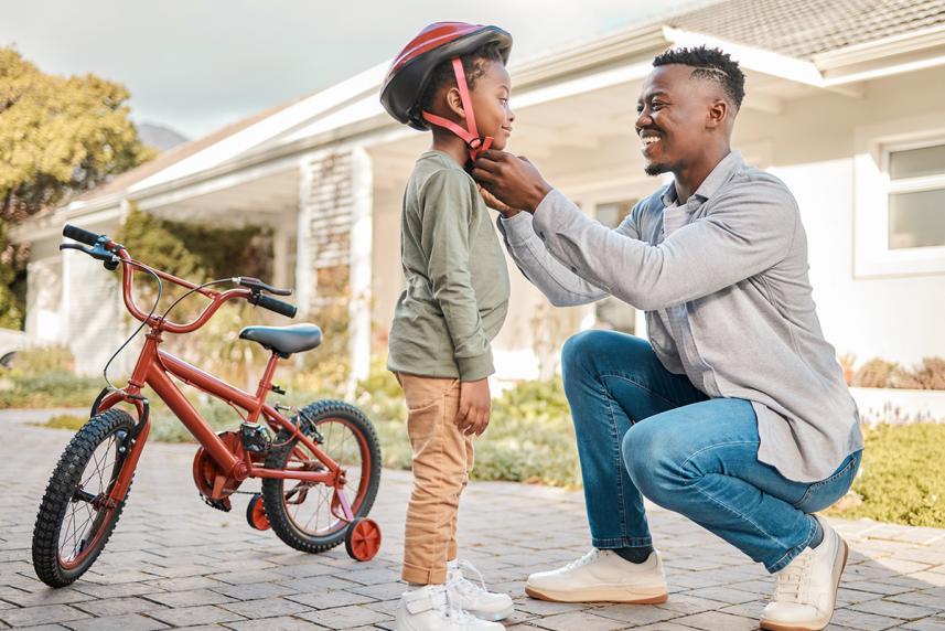 Parent putting a bicycle helmet on their child to prevent brain injury