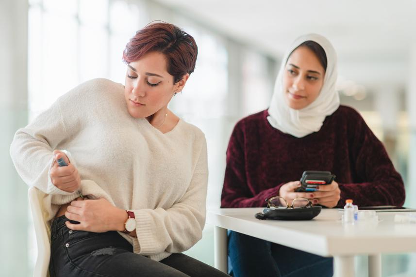 A person supports their loved one with diabetes as they give themselves an insulin shot