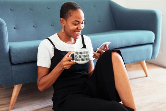 Person on her phone in the morning drinking a cup of coffee