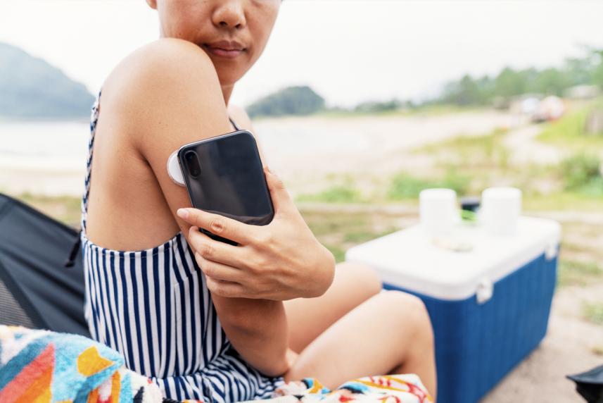 A woman checking her blood sugar levels outside