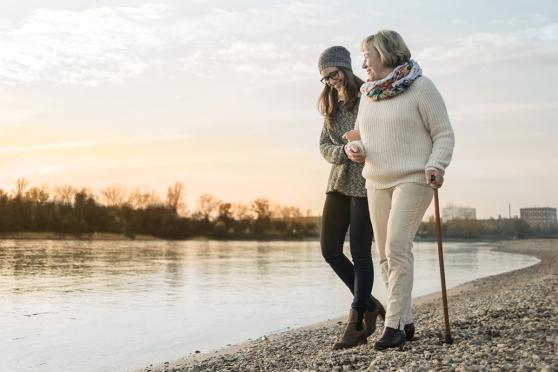 A young woman walking with her mother along a lake