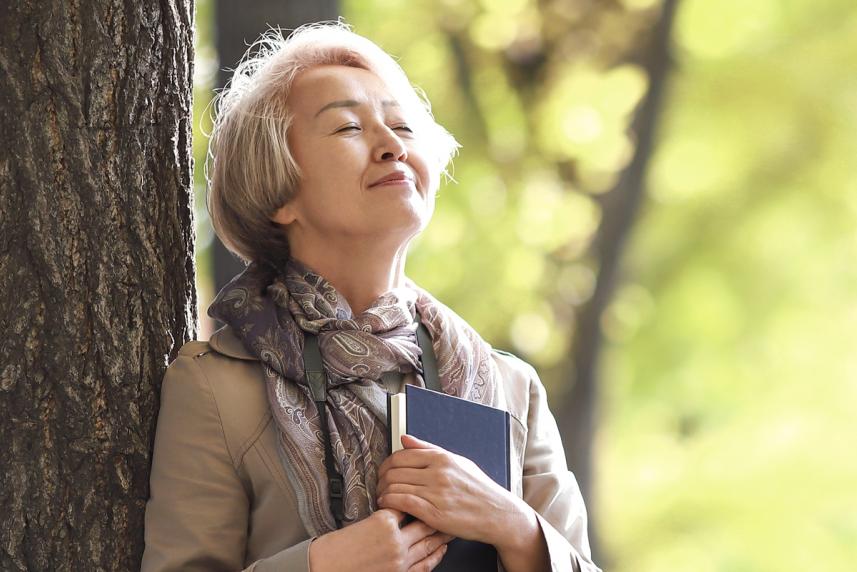 A woman leaning on a tree and relaxing outside