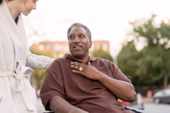 An older man on a chair talking to someone