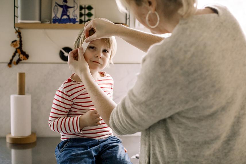 Mother applying band aid from the first aid kit to her child