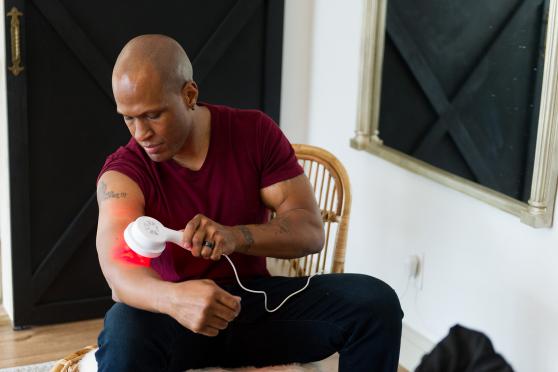 Man treating pain with red light therapy