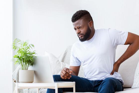 A middle-aged man feeling old with back pain on his couch