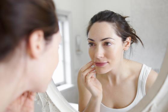 A woman inspecting her face in the mirror