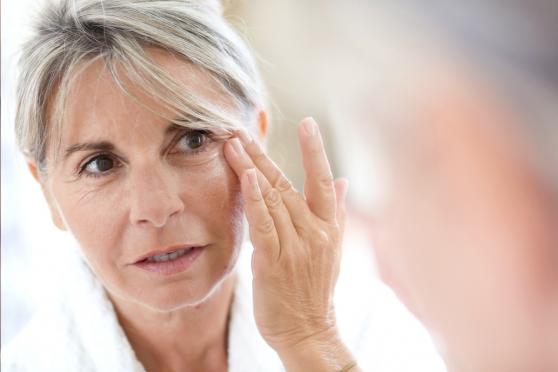 An older woman inspecting her crepey skin