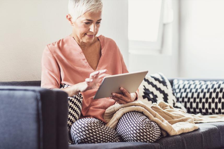 Woman on the couch looking up health insurance information on her table