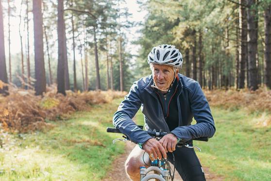 Old man riding a bike near the woods