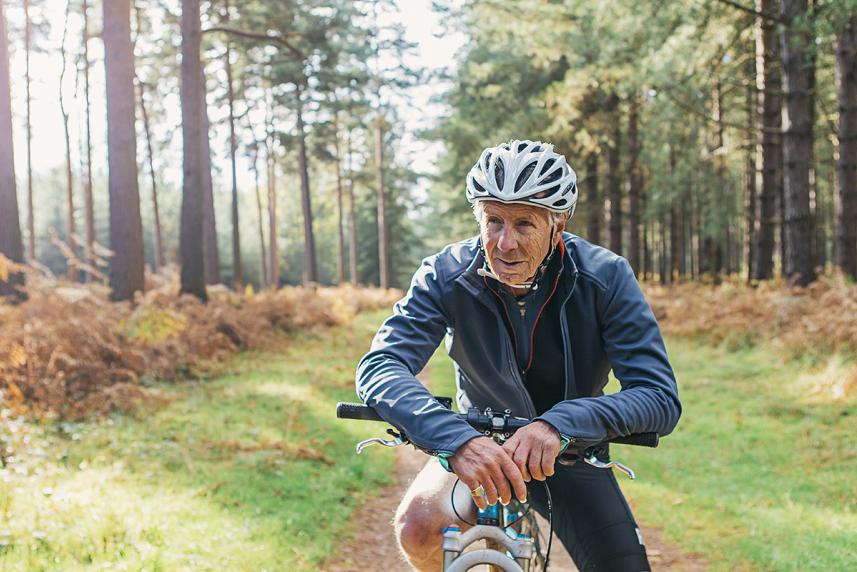 Old man riding a bike near the woods