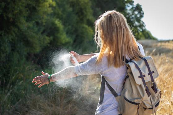 Woman using insect spray on arm