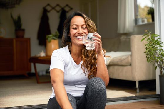 A woman sitting on the floor drinking water